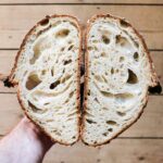 crop unrecognizable person showing yummy cut bread